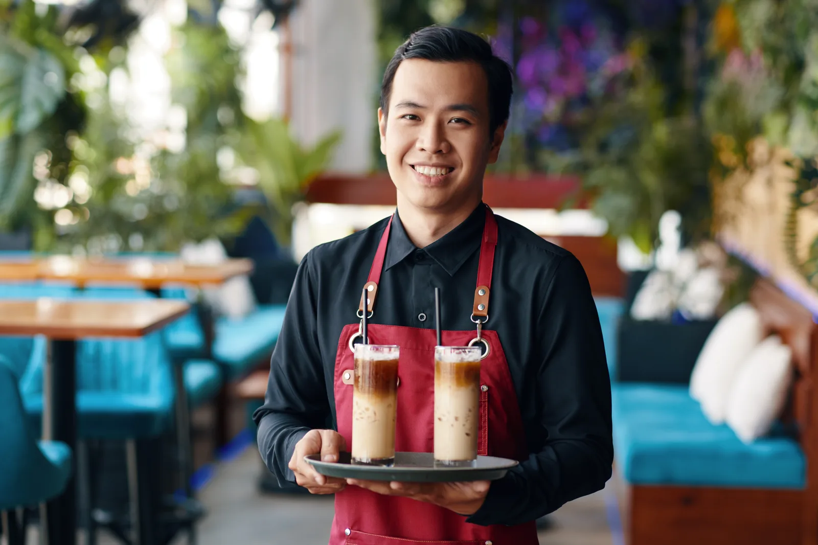 Cafe worker serving two coffees on a tray